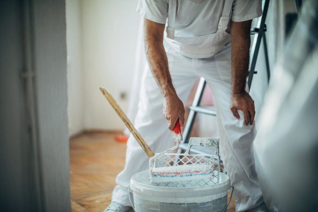 Persona usando un rodillo de pintura y una bandeja de pintura. Herramientas adecuadas para pintar Centro Pinturerías